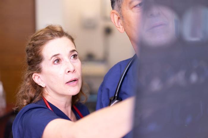 Two clinicians in scrubs studying a diagnostic scan together.