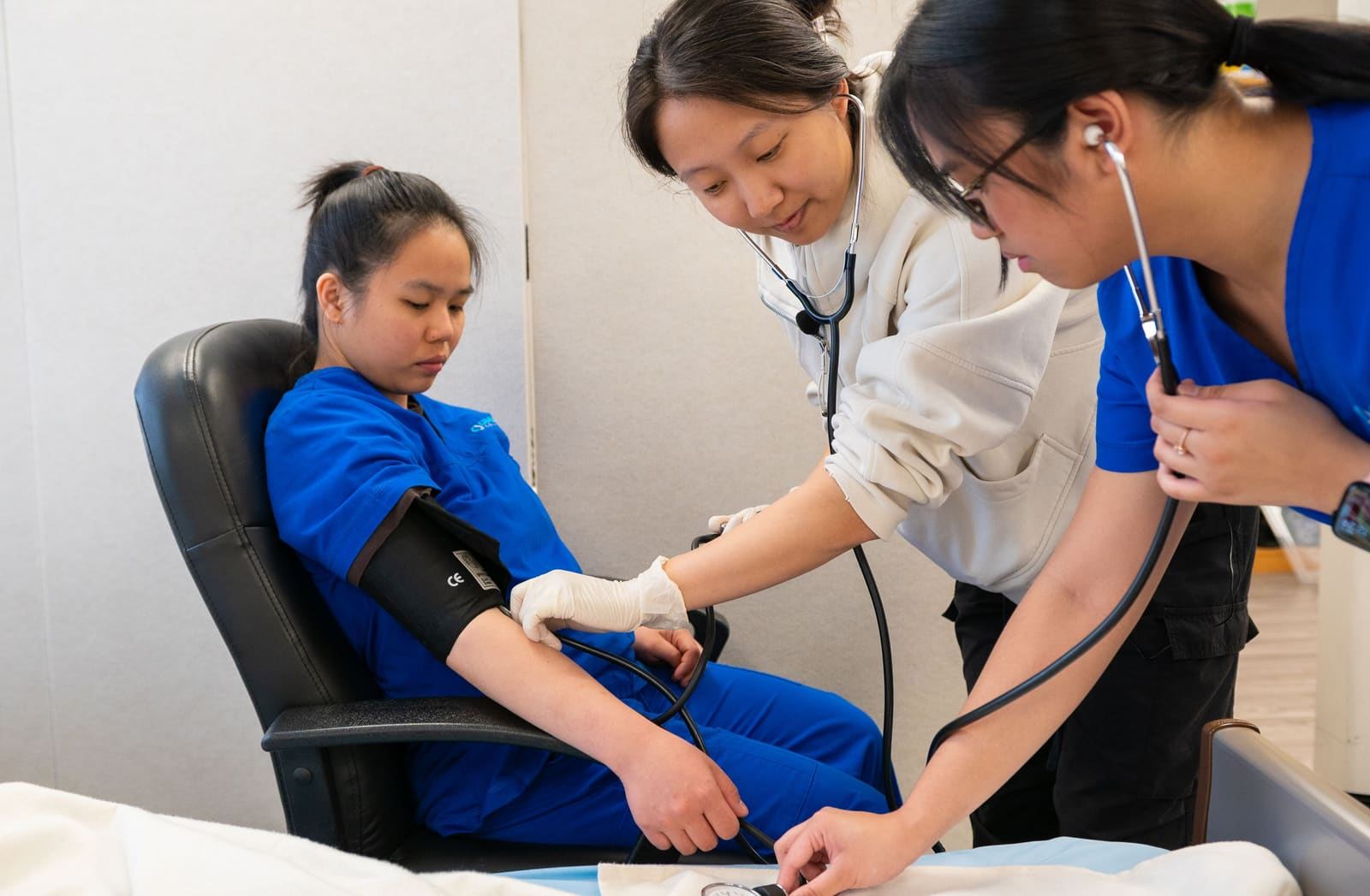 Two nursing students practicing a blood pressure reading on a classmate in a skills lab.